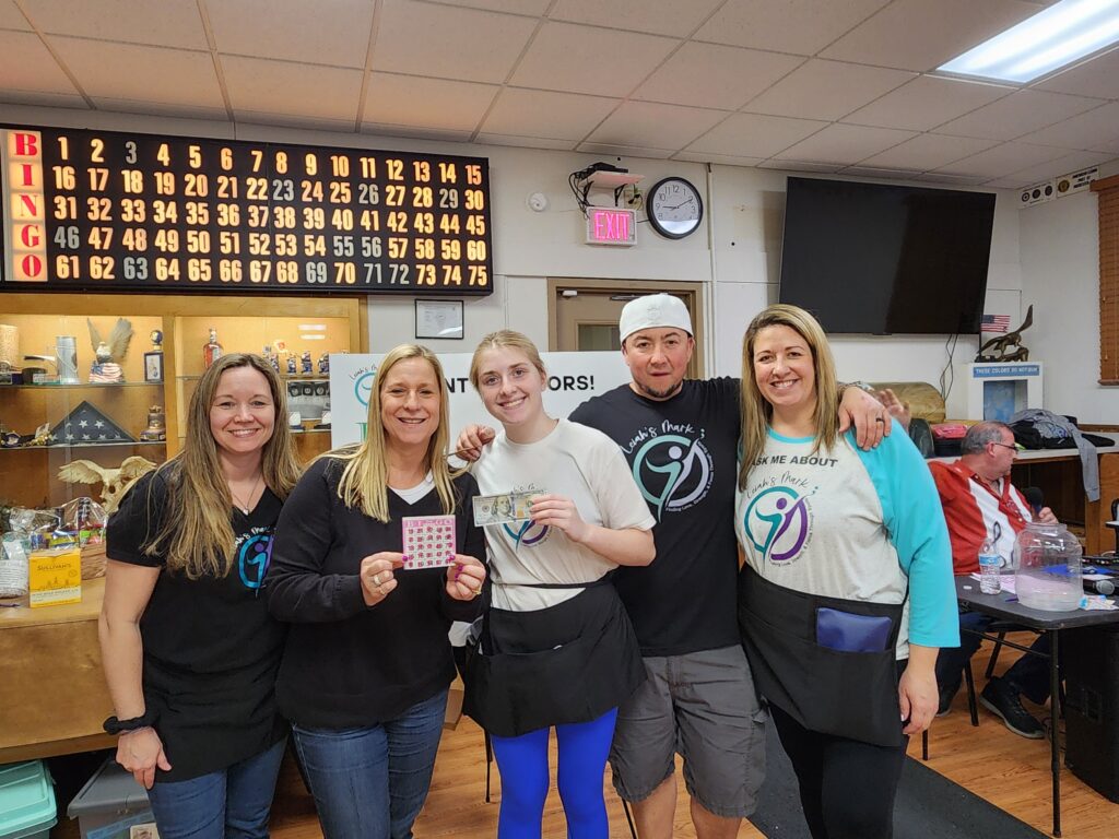 Bingo players pose with winning card and Ben Franklin on winnings.