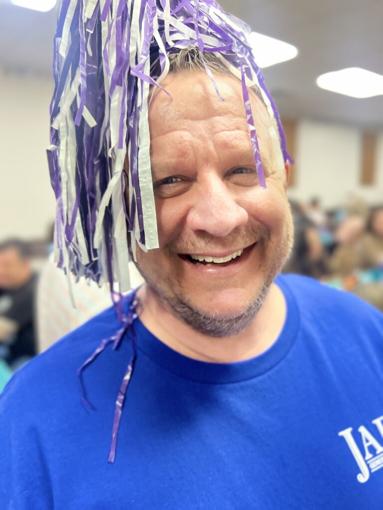 Man with pompom on his head smiling very big