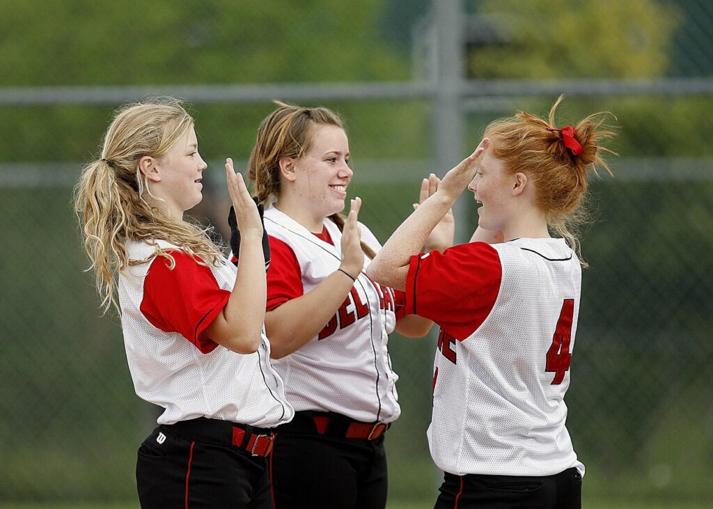 3 players celebrate girls softball win with high fives