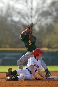 A baseball player slides into second base while another athlete catches the ball