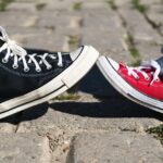 One foot from each of two kids come together wearing athletic gym shoe sneakers outdoors.